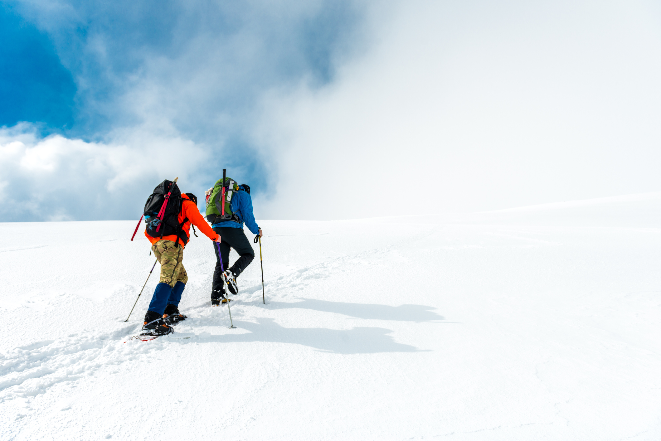 Two mountaineers walking through the mountains covered with snow.